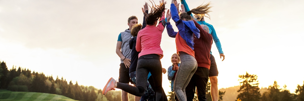 Group of fundraisers jumping in a field and clapping hands together