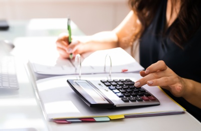 woman calculating her taxes on a calculator with a notebook