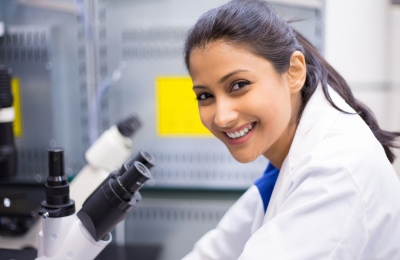 Scientist smiling and using a microscpe