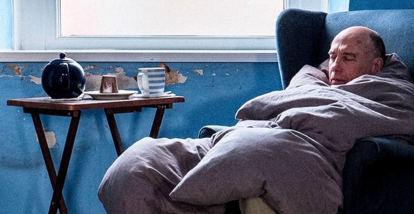 photo of John sitting in chair by photographer Jeremy Jeffs as part of the MEA exhibition "Lives we cannot live"