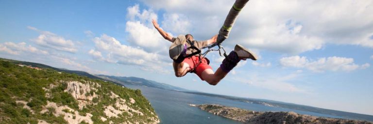 Fundraising event: Bungee Jump. shows man mid jump over a river