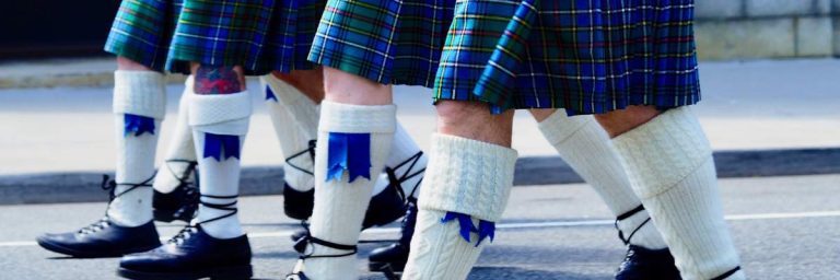 a row of men in kilts walking in unison