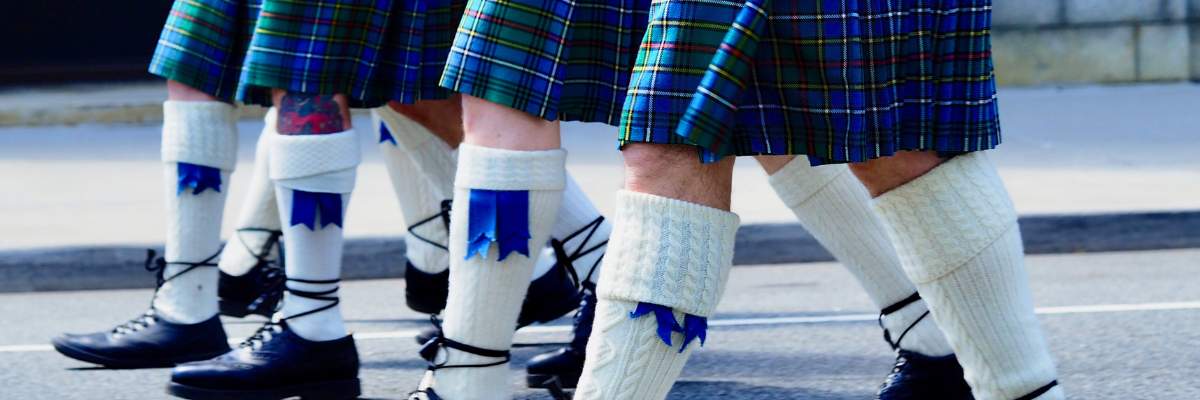 a row of men in kilts walking in unison