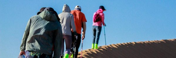 Hikers climbing up a sand dune in a group