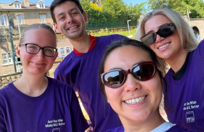Colleagues Richard, Kayla, Reete and Sophie taking part in an 18km walk from Bristol to Bath. They are all smiling, wearing purple ME Association tshirts.
